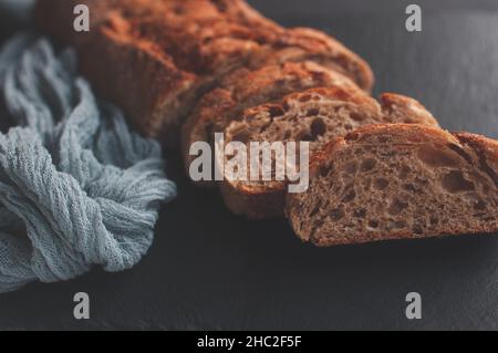 Baguette con selezione di pane francese fatta a mano con tovaglia di garza grigia su sfondo nero Foto Stock