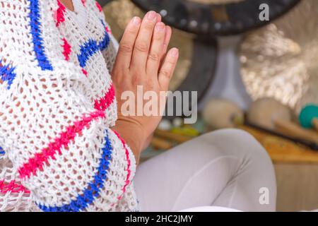 Donna vestita di bianco praticante kundalini yoga seduta a terra e mani insieme Foto Stock