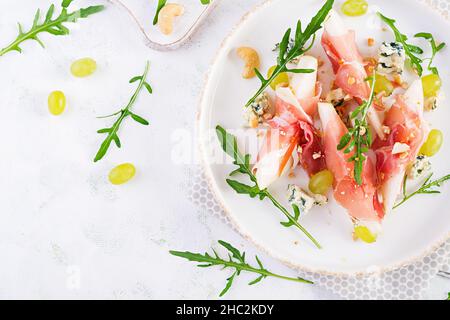 Antipasto con pera, formaggio blu e prosciutto per le vacanze su un piatto bianco. Vista dall'alto, piatto Foto Stock