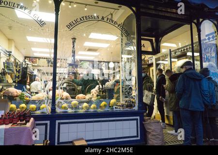 Londra, UK, 23 dicembre 2021: I clienti si trovano fuori dalla macelleria locale, Moen and Sons, nella città vecchia di Clapham. I clienti che raccolgono tacchini, oche o anatre per Natale accodati su un lato. Coloro che vogliono comprare carni, formaggio e prodotti di gastronomia accodati dall'altro lato. Anna Watson/Alamy Live News Foto Stock