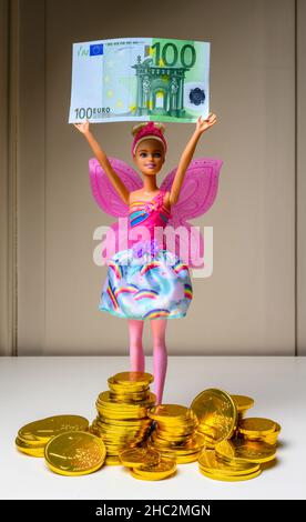 Barbie in possesso di una banconota da 100 euro, pila di cioccolatini in monete d'euro, avvolta con un foglio d'oro a monete da 1 euro in rilievo, Foto Stock