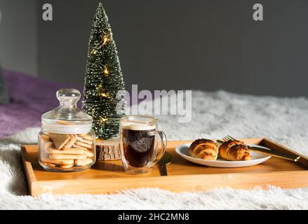 Colazione in camera con tazza di caffè, croissant e biscotti sul vassoio di Natale mattina Foto Stock