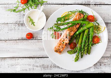 Di salmone al forno guarnito con asparagi e pomodori con erbe aromatiche. Vista superiore Foto Stock