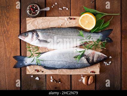 Due materie di spigola con spezie su un vecchio sfondo di legno. Foto Stock