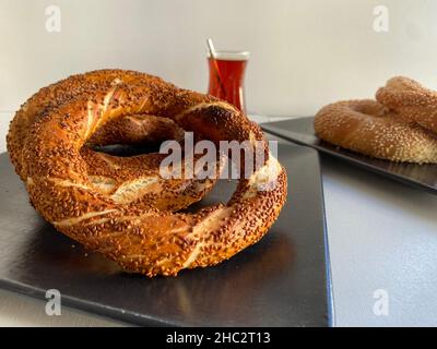 Simit o gevrek, cibo tradizionale turco di strada con tè. Concetto e idea della colazione. Bagel al sesamo. Il nome turco è Simit o gevrek. Foto Stock