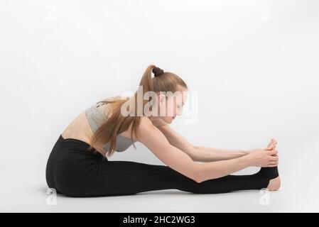 Esercizi di stretching. La giovane donna pratica lo yoga su sfondo bianco. Ragazza è impegnata in ginnastica Foto Stock