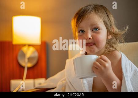 Ritratto di una ragazza carina che beve il tè in una camera da letto. Foto Stock