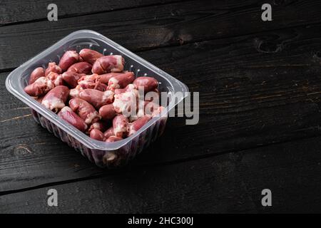 Cuori di tacchino crudi in set di plastica, su sfondo di tavola di legno nero, con spazio di copia per il testo Foto Stock