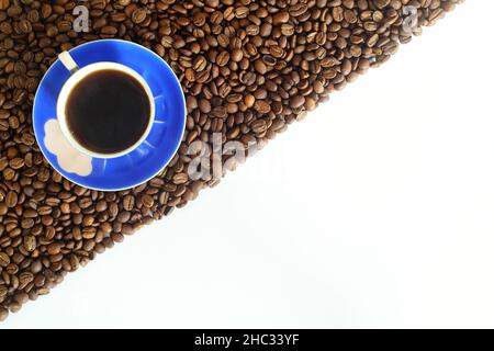 strisce di chicchi di caffè isolate su sfondo bianco. Incorniciare con i chicchi di caffè e la tazza di caffè blu Foto Stock