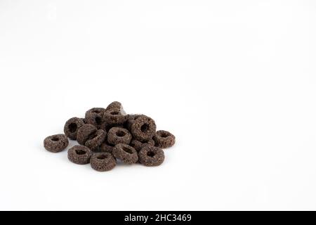 un mucchio di anelli neri di cereali isolati su sfondo bianco, deliziosi e utili anelli colazione cereali, vista laterale primo piano Foto Stock