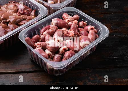 Cuori di pollo crudi di di carne fresca in contenitore di plastica, su vecchio sfondo di legno scuro tavolo Foto Stock