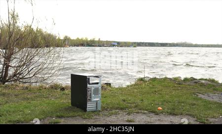 L'uomo rompe un computer dell'unità del sistema del martello. Uomo con un martello da slitta e distrugge il computer in slow motion, fiume e sfondo foresta. Concetto di conf Foto Stock