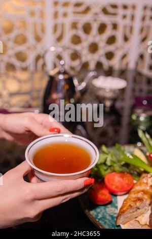 La giovane donna sul divano e con il tè salvia sulla mano Foto Stock