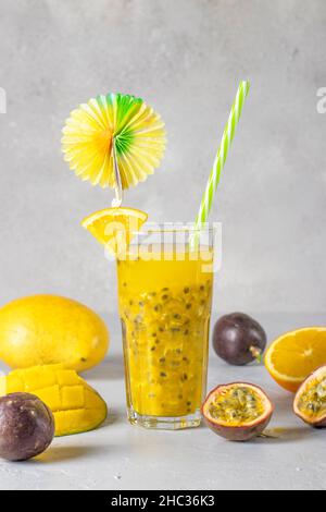 Tropicale fresco di mango, frutto della passione e arancio in alto vetro su sfondo grigio chiaro Foto Stock