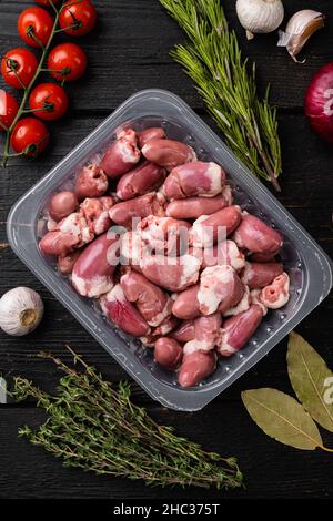 Cuori di pollo in set vassoio di plastica, su sfondo tavolo di legno nero, vista dall'alto piatto Foto Stock