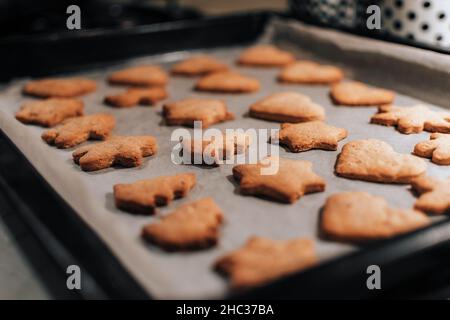 Foto ravvicinata dei biscotti di natale appena sfornati sulla teglia da forno in cucina Foto Stock