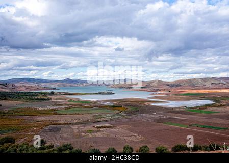 Vista panoramica della campagna agricola con campi arati e lago Foto Stock