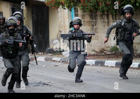 Nablus, Palestina. 23rd Dic 2021. I soldati israeliani hanno visto correre durante la manifestazione.i palestinesi hanno protestato per la ricostruzione dell'insediamento ebraico di Homesh, che è stato evacuato nel 2007. I coloni israeliani hanno distrutto villaggi, case e automobili palestinesi durante la protesta nel villaggio di Burqa. Credit: SOPA Images Limited/Alamy Live News Foto Stock