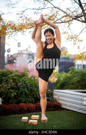 Ginnastica femminile sorridente in equilibrio su una gamba all'aperto Foto Stock