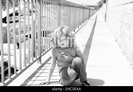 Pausa respiro. Ragazzo relax hunkering giù sul lungomare. Bambino ragazzo prendere riposo breve Foto Stock