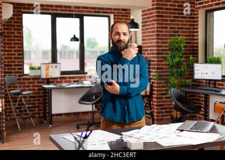 Ritratto dell'imprenditore che guarda in fotocamera mentre lavora alla presentazione di marketing che analizza il rapporto di strategia in ufficio startup. Business uomo pianificazione di investimenti aziendali fare business report Foto Stock