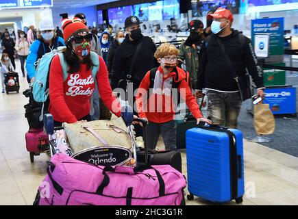 Orlando, Stati Uniti. 23rd Dic 2021. Le persone sono viste con i loro bagagli all'aeroporto internazionale di Orlando due giorni prima di Christmas.a causa dell'aumento e della diffusione di covid-19 e variante di Omicron infezioni, i viaggiatori di vacanza stanno prendendo le precauzioni supplementari ottenendo testato per il virus prima di riunirsi con la famiglia e gli amici. Credit: SOPA Images Limited/Alamy Live News Foto Stock