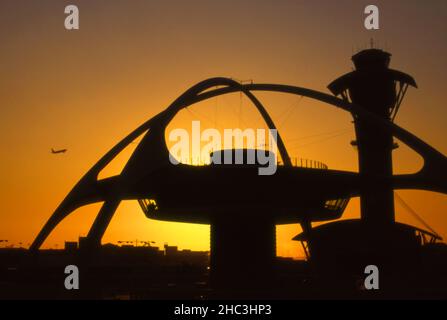 Decollo in aereo a LAX con Theme Building silhouetted by tramonto sole, Los Angeles, CA Foto Stock