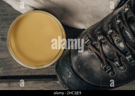 Scarpe o stivali da esterno in pelle con set di manutenzione su sfondo in legno. Foto Stock