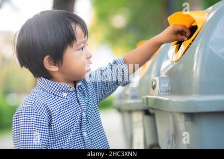 Adorabile ragazzino tenere spazzatura pulita a bin nel parco eco ambientnt concetto Foto Stock