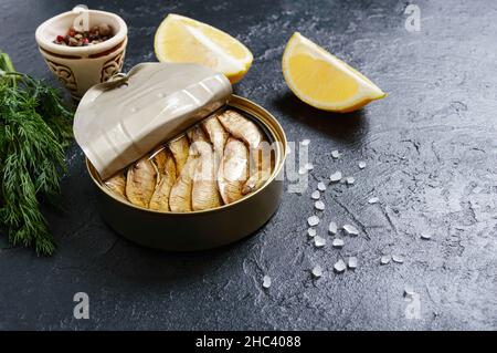 Baltico Spatti di pesce in scatola in lattina con olio su sfondo scuro con spazio copia. Foto Stock