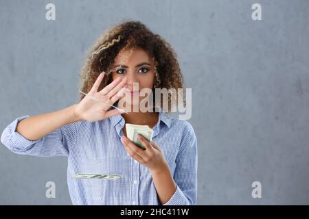 Latino americana giovane donna gettando soldi via dalla mano, mazzo di contanti Foto Stock