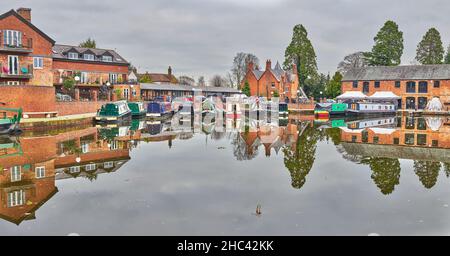 Barche strette accanto a magazzini convertiti in appartamenti e un ristorante presso il bacino di Union Wharf del Grand Union Canal Market Harborough, Inghilterra. Foto Stock