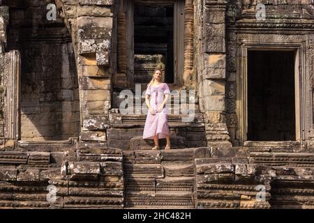 Turista occidentale femminile nel tempio di Bayon nel complesso di Angkor, Cambogia Foto Stock