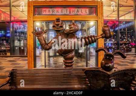 Wallace & Gromit accolgono i clienti che fanno la fila in una giornata bagnata e umida nel centro della città, mentre i rivenditori aprono presto per gli acquirenti natalizi dell'ultimo minuto. Foto Stock