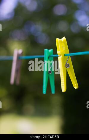 Appendiabiti colorati in plastica e legno sulla linea di vestiario. Spille di abbigliamento in estate. Foto Stock