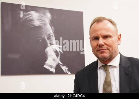 20 dicembre 2021, Amburgo: Andy Grote (SPD), senatore per gli interni e lo sport ad Amburgo, si trova nel suo ufficio presso il Ministero degli interni di fronte a una foto che mostra l'ex Cancelliere tedesco e l'ex Senatore di Amburgo per l'interno Helmut Schmidt. (Al dpa 'il senatore interno di Amburgo Grote teme la radicalizzazione degli avversari della vaccinazione') Foto: Marcus Brandt/dpa Foto Stock