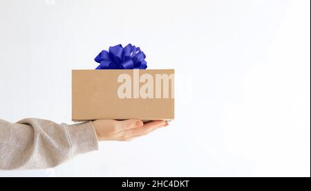 Consegna espressa. Una giovane donna in felpa tiene una scatola di cartone con un arco molto peri. Shopping online sale Foto Stock