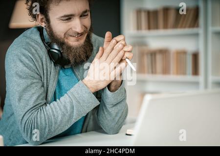 Shy Student ha una lezione video online dal suo portatile nella sua Home Library. Lo studente ha l'apprendimento a distanza durante il periodo di quarantena. Scaffali pieni di libri sfondo. Primo piano. Foto di alta qualità Foto Stock