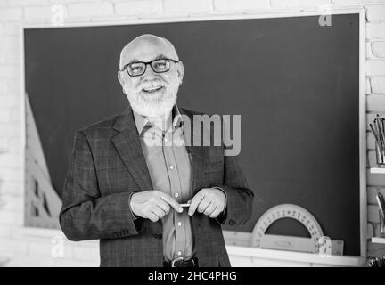 Condivisione delle conoscenze. Più strumenti introdotti nelle aule di tutti i giorni. Insegnante di uomo anziano presso la lavagna. Ritorno a scuola. Insegnante di vecchia generazione scolastica Foto Stock