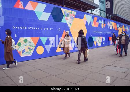 La gente cammina davanti all'ex sito di ristrutturazione del negozio di punta di Debenham in Oxford Street. Londra, Regno Unito 24 dicembre 2021. Foto Stock