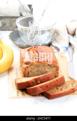 Pane fatto in casa pane di torta di Banana affettato su un tavolo primo piano. Verticale, stile rustico bianco, concetto di panetteria. Foto Stock