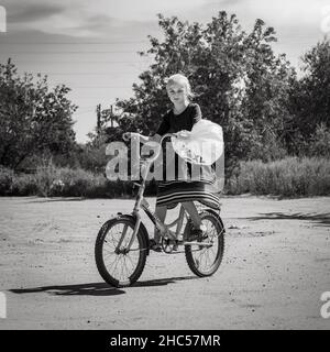 18th del 2020 luglio, Russia, Altay, ragazza su una bicicletta rurale scena in bianco e nero Foto Stock