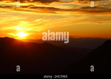 Tramonto giallo con il sole sulle montagne nel passo Caraturek ad Altai con il sole, con sagome di montagne contro il cielo in estate Foto Stock