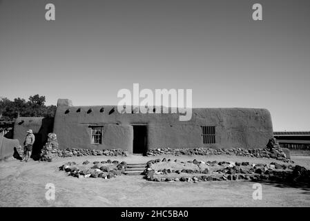 I visitatori esplorano le storiche strutture in adobe del 19th secolo presso il complesso storico vivente El Rancho de las Golondrinas vicino a Santa Fe, New Mexico. Foto Stock