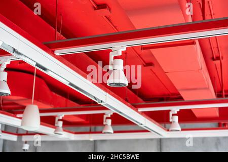 Unità di climatizzazione a cassetta montate a soffitto con altre parti del sistema di ventilazione (tubi, cavi e sfiati) situate all'interno della sala commerciale con Foto Stock