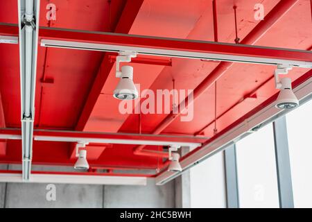 Unità di climatizzazione a cassetta montate a soffitto con altre parti del sistema di ventilazione (tubi, cavi e sfiati) situate all'interno della sala commerciale con Foto Stock