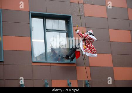 Mosca, Russia. 24th Dic 2021. Un operatore di emergenza russo vestito come Moroz di D bilancia il muro di un ospedale per bambini mentre saluta i bambini per il prossimo anno nuovo a Mosca, Russia, il 24 dicembre 2021. Credit: Alexander Zemlianichenko Jr/Xinhua/Alamy Live News Foto Stock