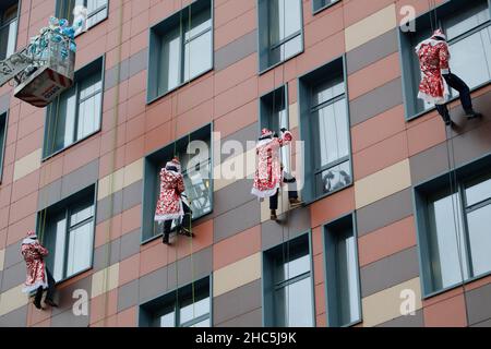 Mosca, Russia. 24th Dic 2021. Gli operatori di emergenza russi vestiti come Moroz di D scalano il muro di un ospedale per bambini mentre salutano i bambini per il prossimo anno nuovo a Mosca, Russia, il 24 dicembre 2021. Credit: Alexander Zemlianichenko Jr/Xinhua/Alamy Live News Foto Stock