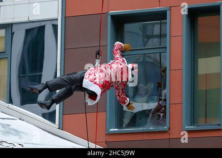 Mosca, Russia. 24th Dic 2021. Un operatore di emergenza russo vestito come Moroz di D bilancia il muro di un ospedale per bambini come saluta un bambino per il prossimo anno nuovo a Mosca, Russia, il 24 dicembre 2021. Credit: Alexander Zemlianichenko Jr/Xinhua/Alamy Live News Foto Stock