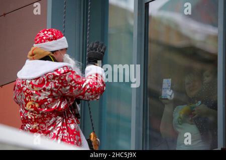 Mosca, Russia. 24th Dic 2021. Un operatore di emergenza russo vestito come Moroz di D bilancia il muro di un ospedale per bambini come saluta un bambino per il prossimo anno nuovo a Mosca, Russia, il 24 dicembre 2021. Credit: Alexander Zemlianichenko Jr/Xinhua/Alamy Live News Foto Stock